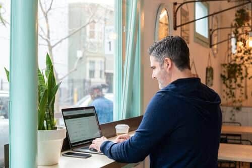 Homme assis devant un ordinateur dans un café